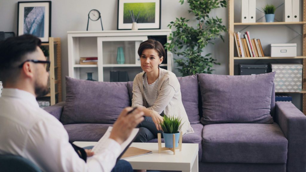 Ein Mann sitzt auf einem Sofa und unterhält sich mit einer Frau.