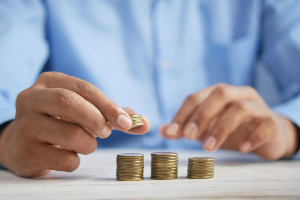 Nahaufnahme von Händen, die Goldmünzen stapeln, als Symbol für finanzielles Wachstum und Ersparnisse.