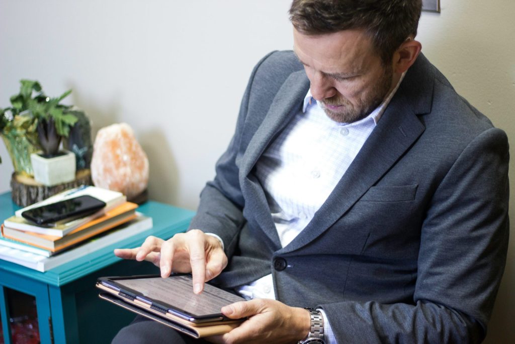 Ein Mann im Anzug hält ein Tablet in der Hand.