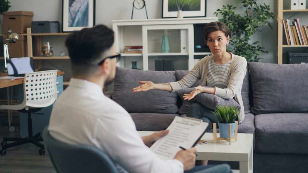 Ein Mann sitzt auf einem Sofa und unterhält sich mit einer Frau.
